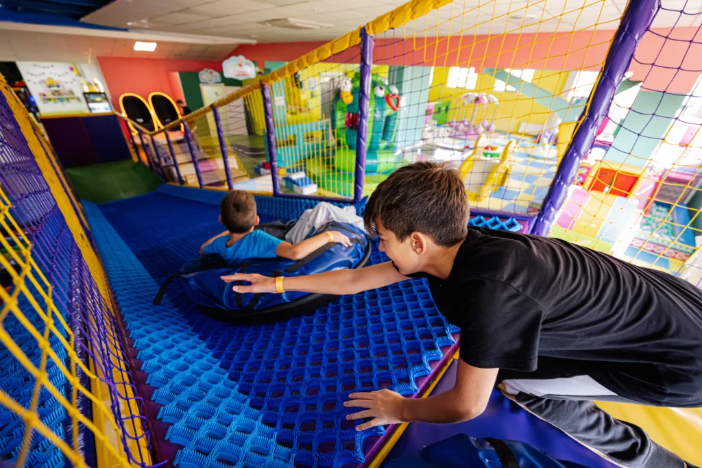 Kids having fun racing down slides in an indoor playground.
