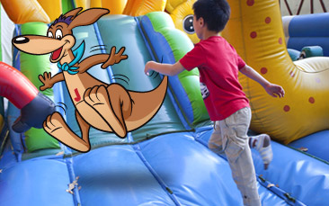 A boy and a kangaroo character playing on an inflatable slide