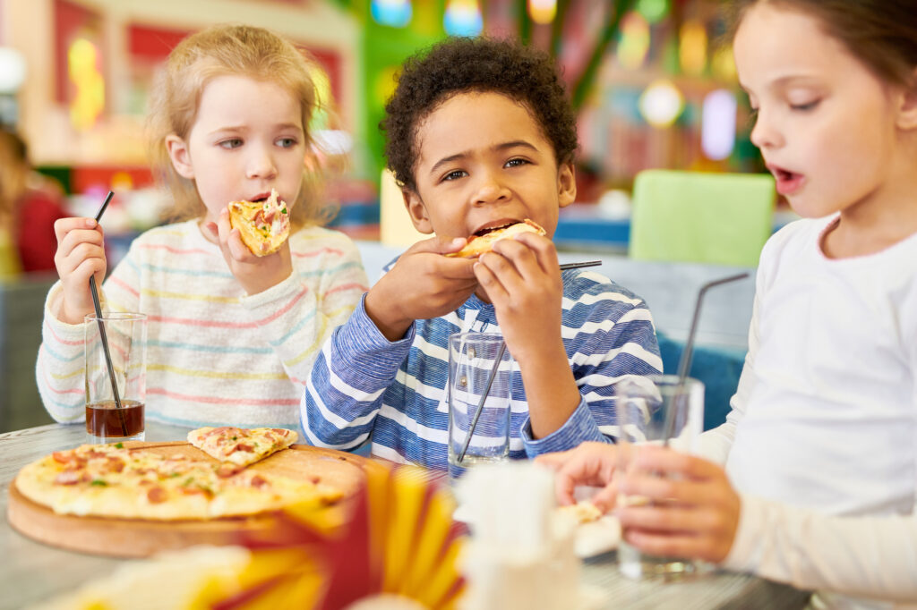 Kids enjoying pizza in an indoor playground.