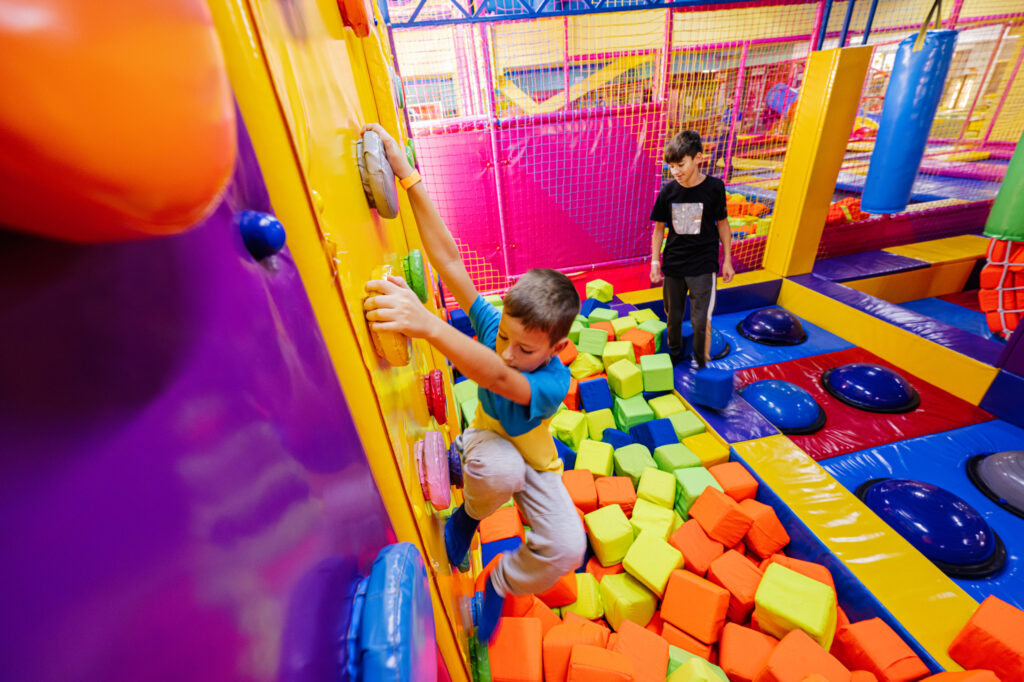 Kids play and climb on indoor playground equipment.